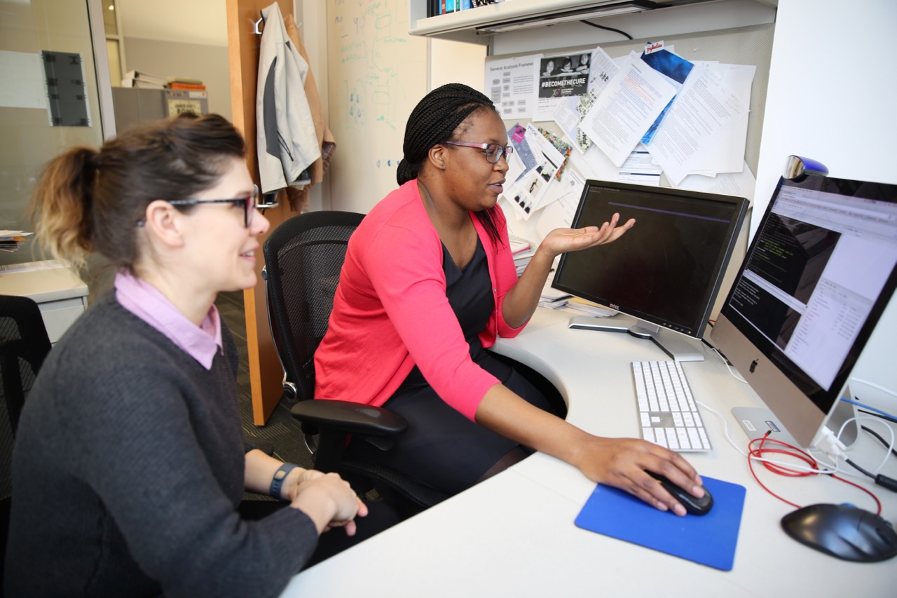 Dr. Nyasha Chambwe, a postdoctoral fellow in the Shmulevich Lab at Institute for Systems Biology, discusses some data analysis with colleague Summer Elasady.
