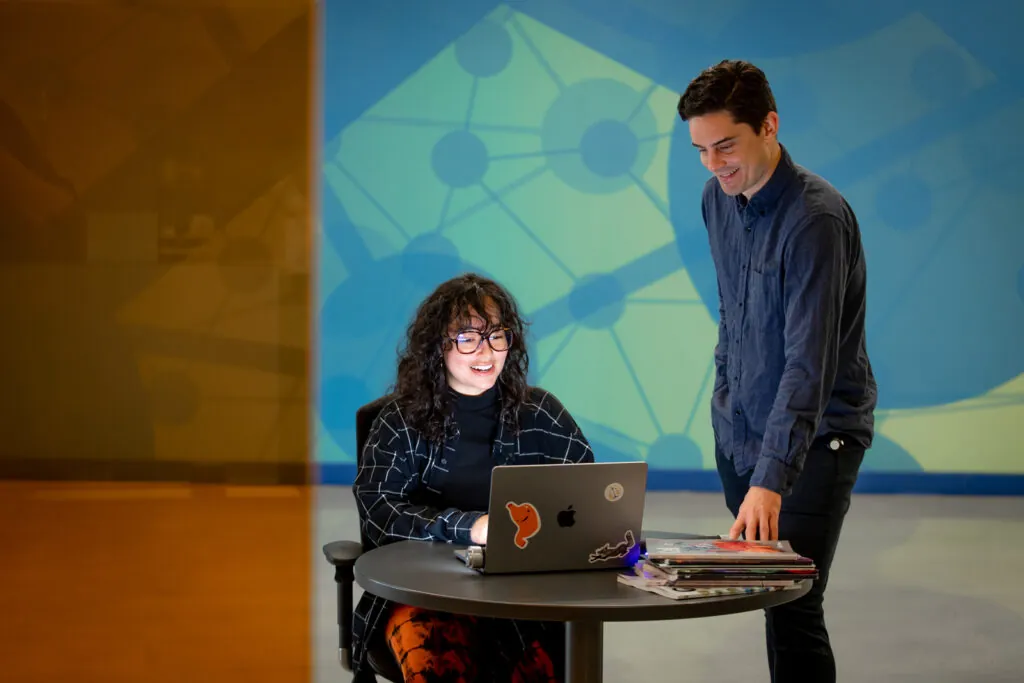 two people working together on a laptop