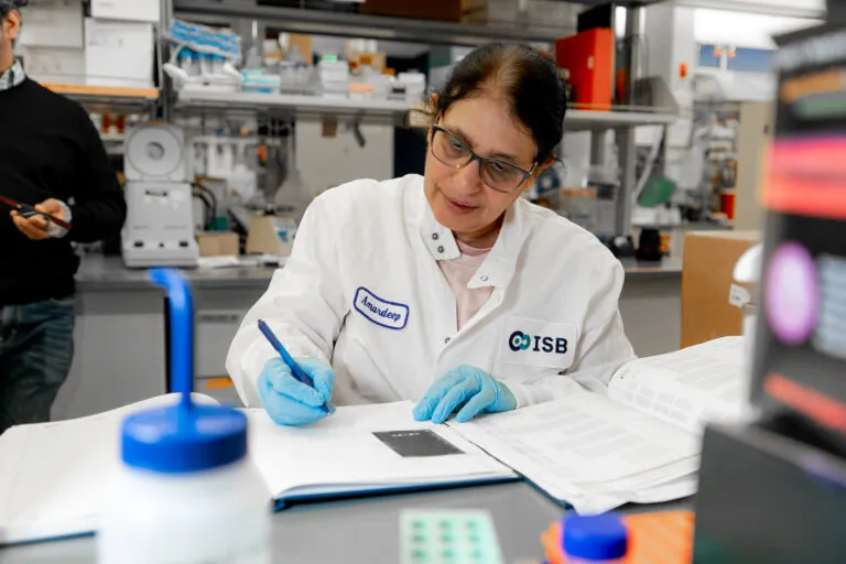 woman working in a lab, writing in a book