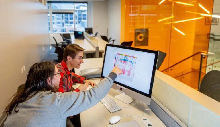 two employees looking at a computer screen in an office